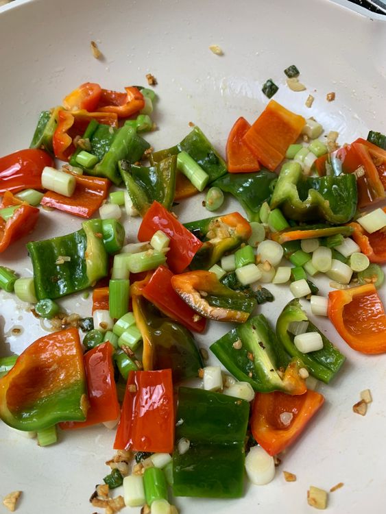 Step 6.1: Add the capsicums and spring onion whites; stir-fry for 1–2 minutes until slightly tender but still crisp