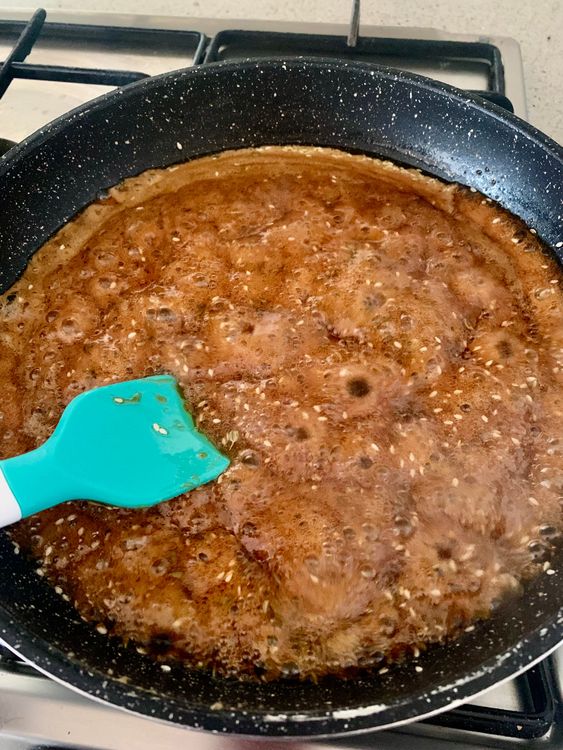 Step 2.1: Once the jaggery syrup thickens, add ghee, sesame seeds, and saunf