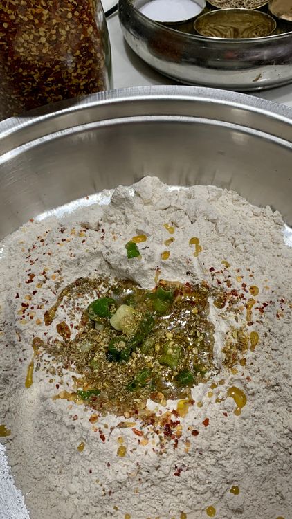 Step 1.1: Mix the whole wheat flour, semolina, carom seeds, cumin seeds, coriander powder red chilli flakes, turmeric powder, garam masala, 1 tbsp oil and a pinch of salt
