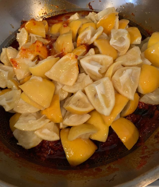 Step 2.1: Add the cut lemon pieces into the pan, ensuring they are well-coated with the spiced oil mixture
