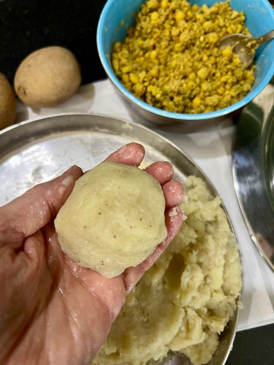 Step 1.1: Take a small ball of the potato mix, flatten it, and fill with a tablespoon of dal mix