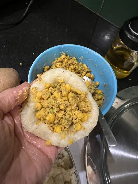 Step 1.2: Take a small ball of the potato mix, flatten it, and fill with a tablespoon of dal mix