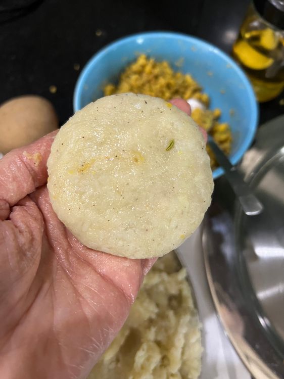 Step 1.3: Take a small ball of the potato mix, flatten it, and fill with a tablespoon of dal mix