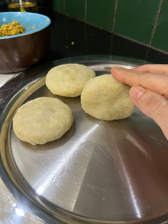 Step 1.4: Take a small ball of the potato mix, flatten it, and fill with a tablespoon of dal mix