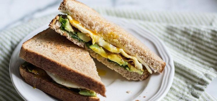 Step 1.1: Assemble the sandwiches by adding the cooked eggs to the four slices of bread with spinach and avocado, then top with the other four pieces of bread with melted aged cheddar cheese