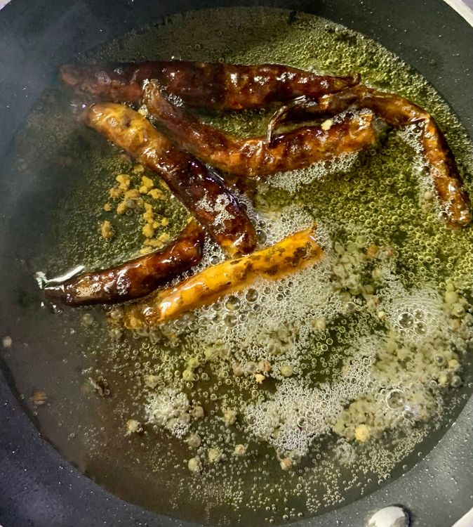 Step 3.1: Then add the curry leaves and dry red chillies