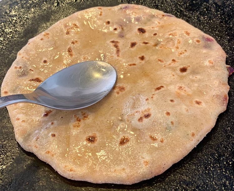 Step 2.2: Brush the paratha with a little oil and flip it again and press gently with a flat ladle