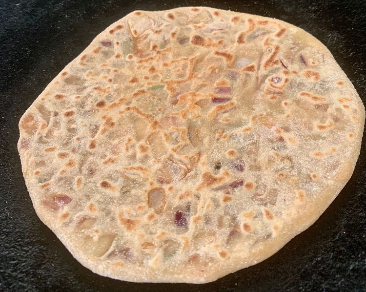 Step 2.1: When partially cooked (with little brown spots), flip the paratha on the tawa, and let it cook for about a minute
