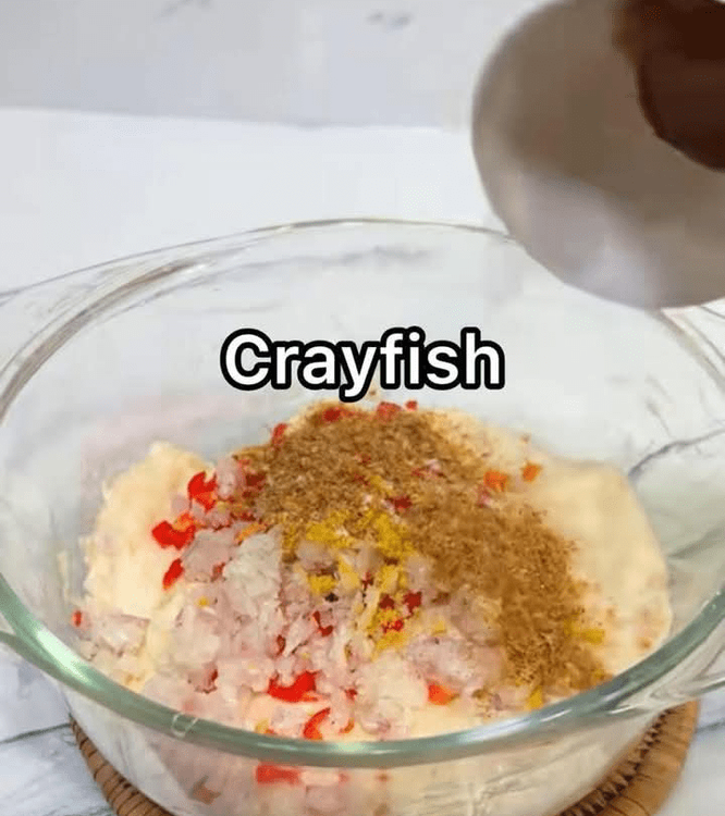Step 1.4: Add the chopped peppers, onion, salt, seasoning cubes, and ground crayfish to the grated water yam in the bowl