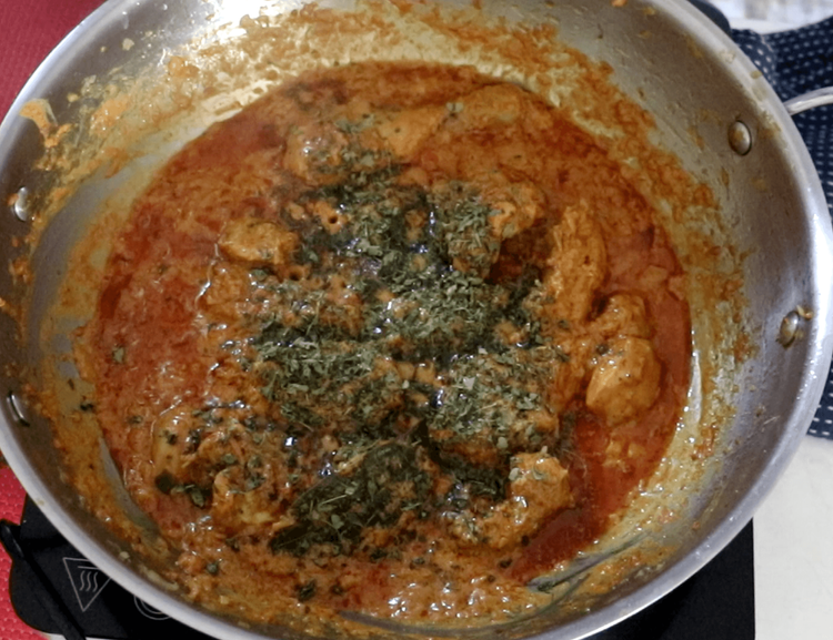 Step 2.1: Sprinkle the kasuri methi over the chicken, stirring it gently into the curry