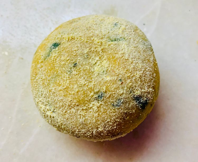 Step 2.2: Take a dough ball, dust it with a bit of cornmeal flour and place it on the rolling board