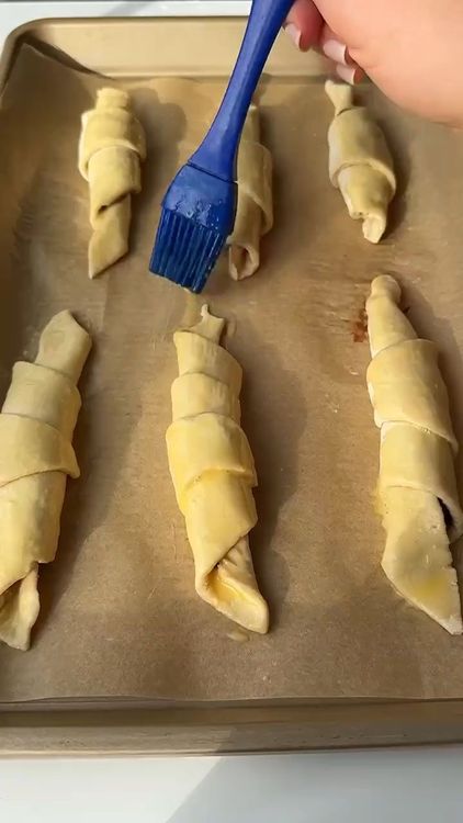 Step 1.1: Brush each rolled croissant with egg wash