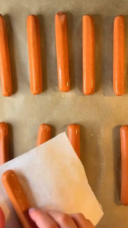 Step 2.1: Wrap the dough strips around each hot dog, leaving a gap for the eyes