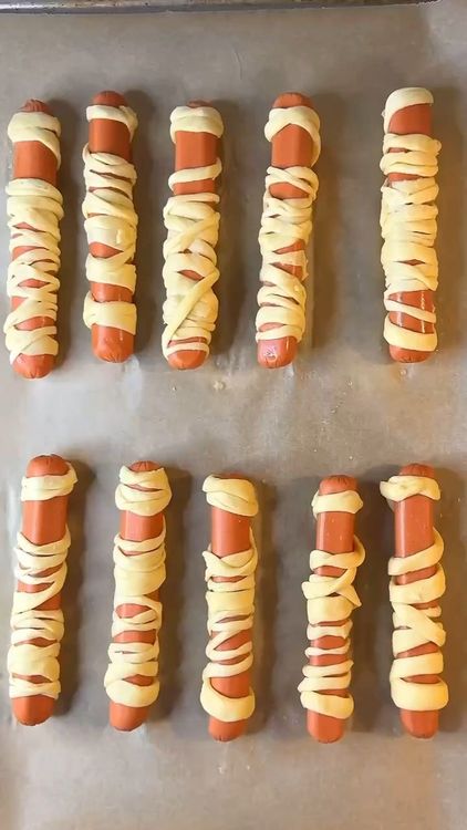 Step 2.2: Wrap the dough strips around each hot dog, leaving a gap for the eyes