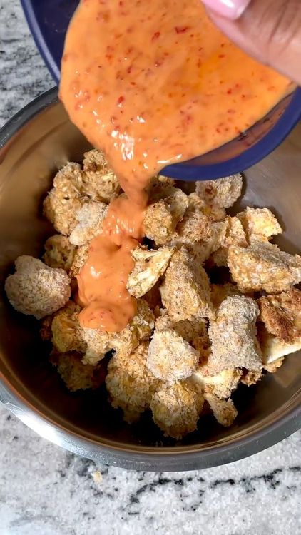 Step 1.1: Once the cauliflower is done baking, drizzle the Bang Bang sauce over the top and toss to coat