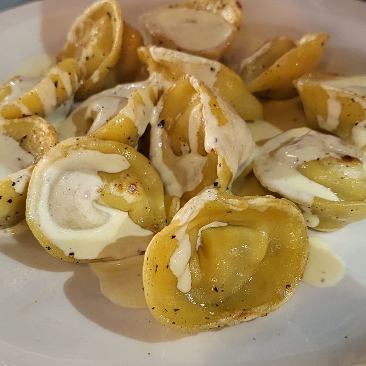 Step 5.1: Place a few sautéed tortellinis into each pasta bowl, pour over some parmesan cream, and garnish your dish with a little extra grated parmesan cheese