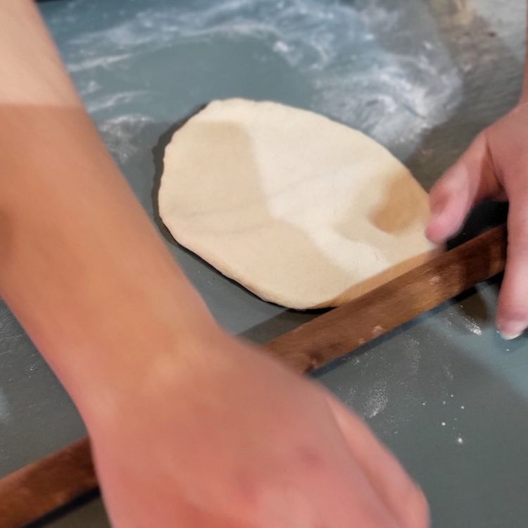 Step 1.2: On a lightly floured surface, push down each dough ball, then roll the dough from the center outwards