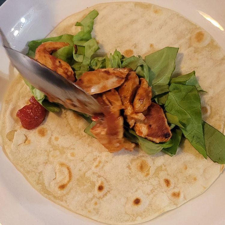 Step 2.1: Now build your tacos, starting with lettuce in the center, topped with chicken, tomatoes, cucumber, red onions, cheddar cheese, and avocado