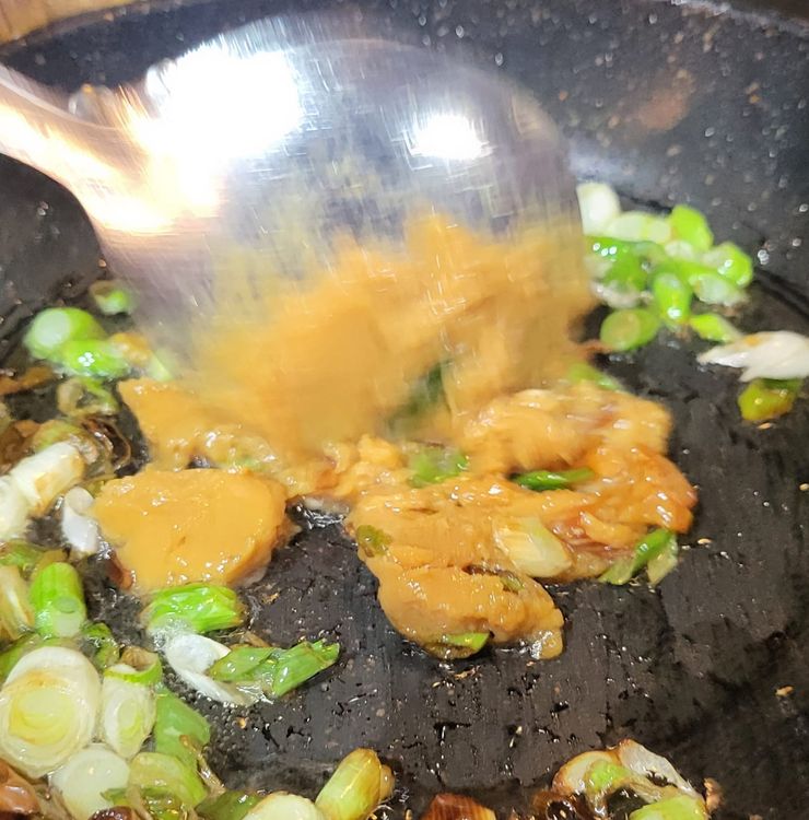 Step 1.1: Heat a wok to medium heat, add the last bit of vegetable oil, then add half of the spring onions