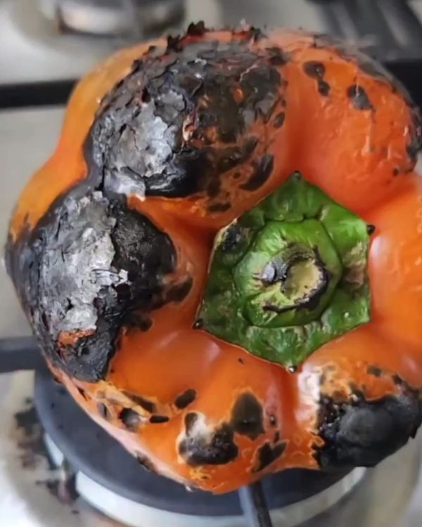 Step 1.1: Hold the red peppers over a gas flame until the skin is charred and blackened