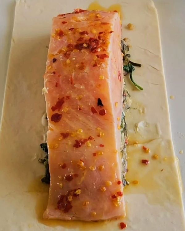 Step 3.1: Place the marinated salmon in the center of the pastry sheet and top it with the creamy spinach mixture