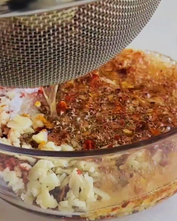Step 3.1: Strain the hot oil directly into the bowl with the spice mix