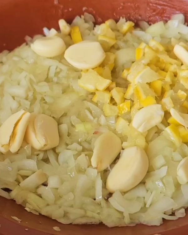 Step 2.1: Place the chopped onions, garlic, and lemon at the base of the tagine or a heavy-bottomed pot
