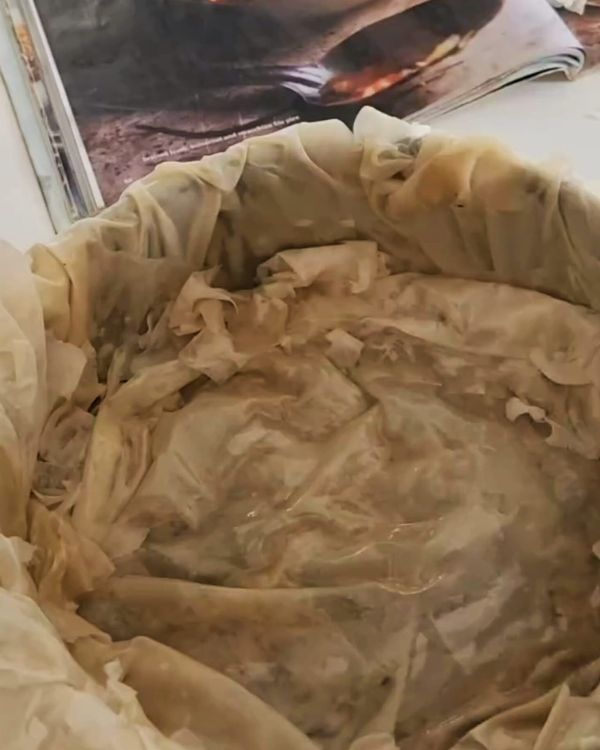 Step 4.1: Fold any overhanging pastry over the filling, then layer 2-3 more sheets of filo on top, brushing each with melted butter