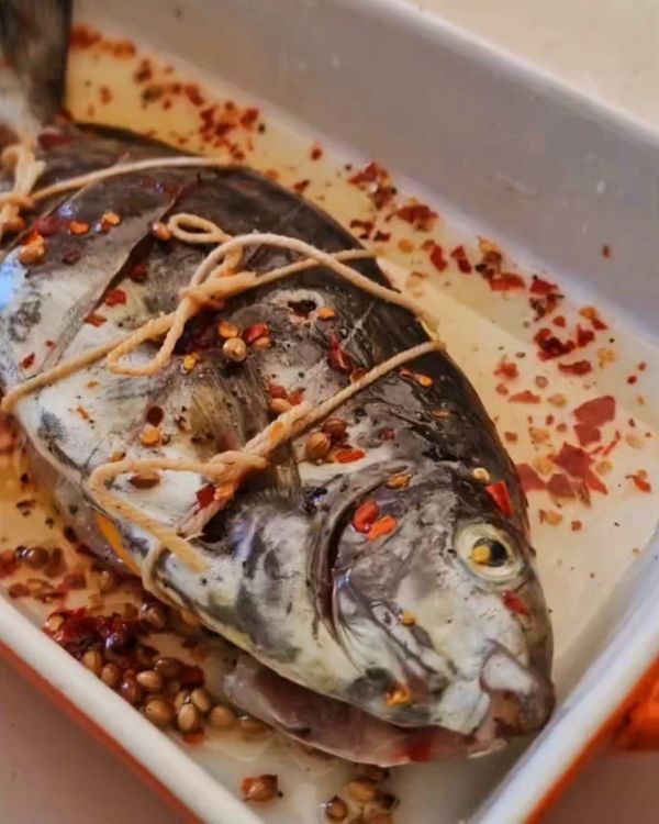 Step 2.1: Stuff the fish cavity with orange slices, then tie it securely with kitchen twine to hold the stuffing in place