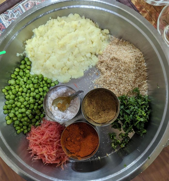 Step 2.1: Add the chopped onions, chopped coriander leaves, boiled green peas, grated carrots, green chilli, salt, bread crumbs, red chilli powder, black pepper and mix it all properly