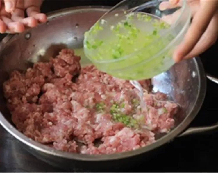 Step 2.1: In a large mixing bowl, mix the ginger and green onion water with the ground pork in three batches