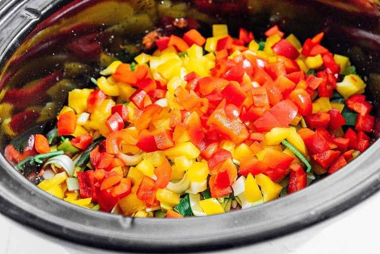 Step 1.2: In your slow cooker, layer the brown rice, crushed tomatoes, half a can of water, black beans, garlic, spices, and all the veggies