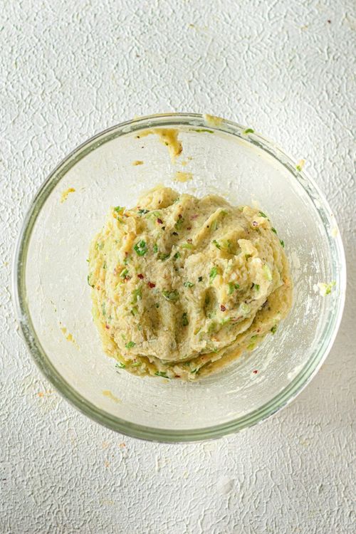 Step 1.2: Stir in the all-purpose flour, salt, pepper, garlic powder, onion powder, chili flakes, oregano, and chopped parsley into the potatoes and mix to create a dough