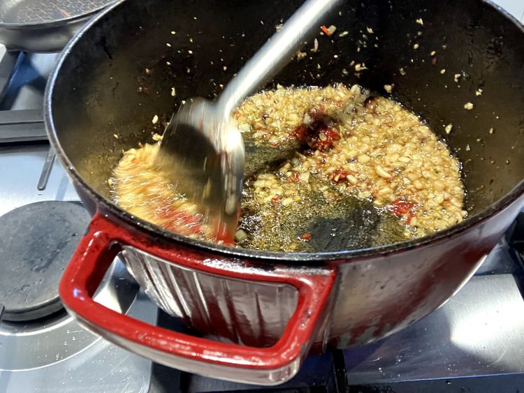 Step 2.5: Add the chillies, basil, and oregano and cook for a further minute, ensuring everything is evenly distributed