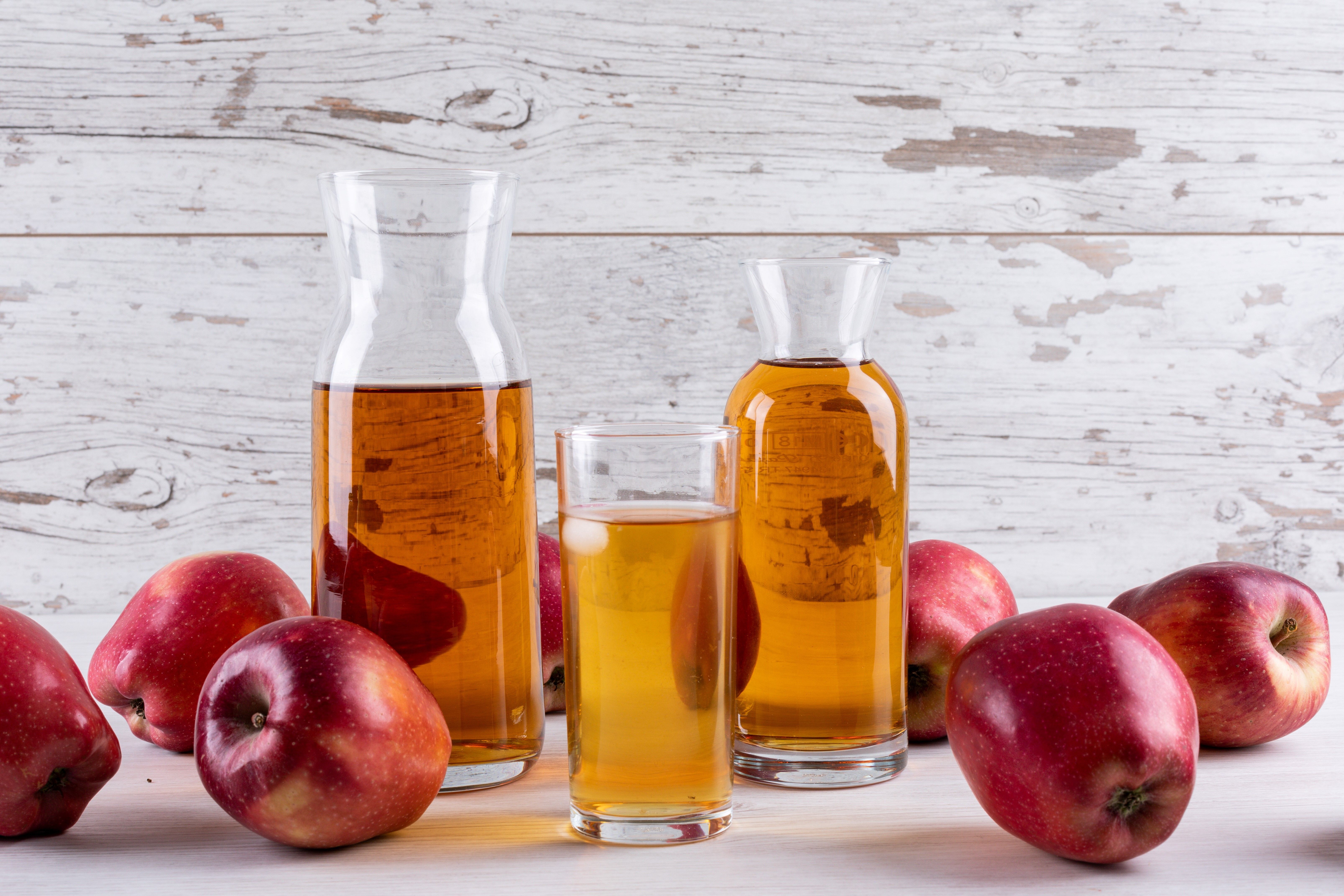 side-view-apple-juice-with-red-apples-white-wooden-table
