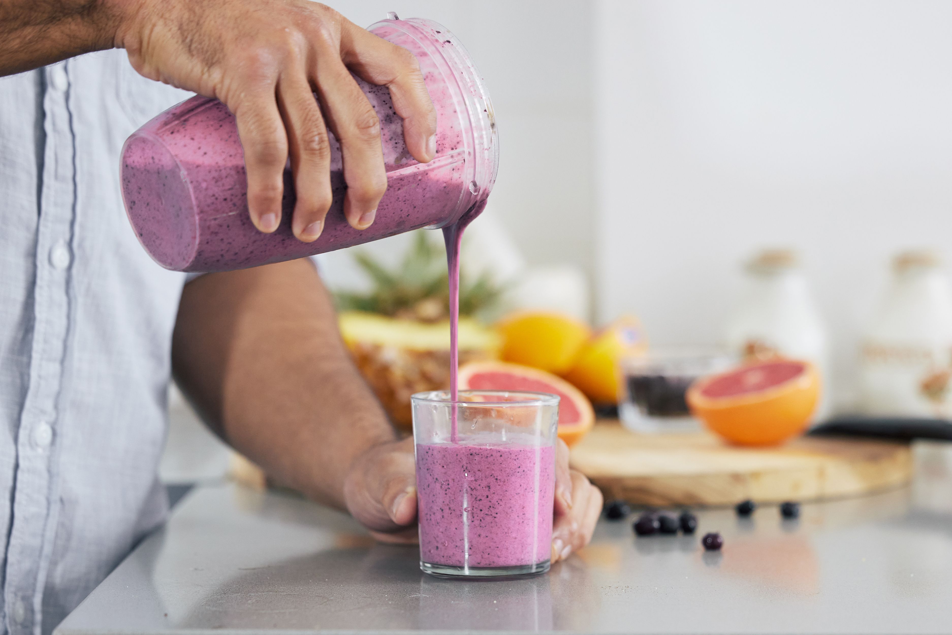 Man pouring smoothie into a glass for a healthy breakfast after reading smoothie recipes protein